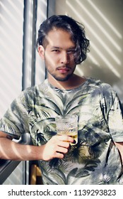 Young Handsome Man With A Glass Of Whiskey Standing Near Window