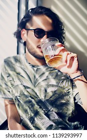 Young Handsome Man With A Glass Of Whiskey Standing Near Window