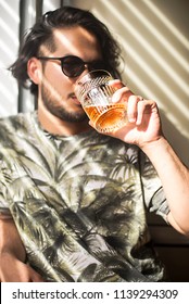 Young Handsome Man With A Glass Of Whiskey Standing Near Window