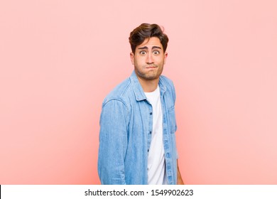 young handsome man and goofy  crazy  surprised expression  puffing cheeks  feeling stuffed  fat   full food against pink background