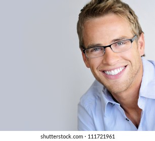 Young handsome man with great smile wearing fashion eyeglasses against neutral background with lots of copy space