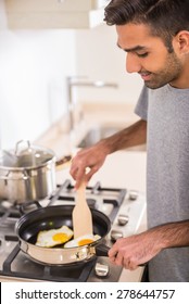 Young Handsome Man In Grey T-shirt Making Omelet For Breakfast.