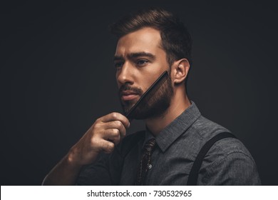 Young Handsome Man Grooming His Beard With A Comb