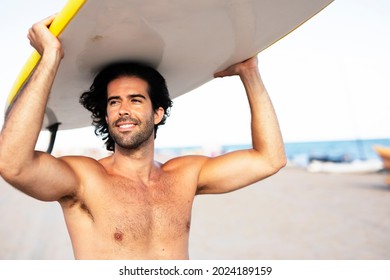 Young handsome man with his surfboard. Happy man relaxing at the beach