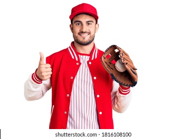 Young handsome man holding baseball gloves smiling happy and positive, thumb up doing excellent and approval sign  - Powered by Shutterstock