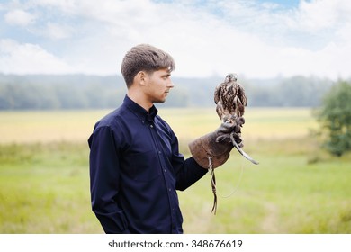 Young handsome man holding a falcon on his arm - Powered by Shutterstock