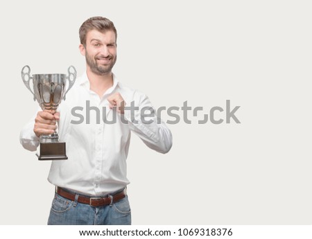 young handsome man holding a trophy wearing white t shirt, success expression . person isolated against monochrome background