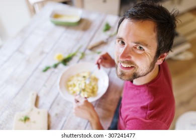 Young Handsome Man In The Kitchen Eating Salmon Tagliatelle