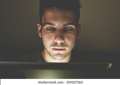 Young Handsome Man At Laptop Computer With Light Reflection From The Screen To The Face - Technology, Internet And People Concept