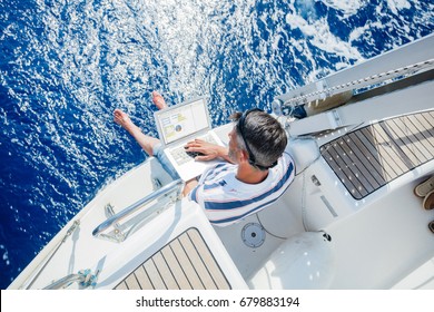 Young and handsome man with laptop computer on sailboat