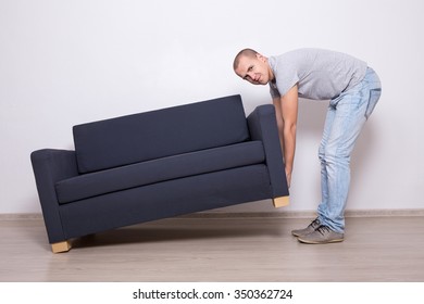 Young Handsome Man Lifting Up Sofa Or Couch