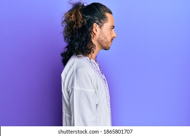 Young Handsome Man With Long Hair Wearing Bohemian And Hippie Shirt Looking To Side, Relax Profile Pose With Natural Face With Confident Smile. 