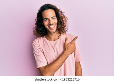 Young handsome man with long hair wearing casual clothes smiling cheerful pointing with hand and finger up to the side  - Powered by Shutterstock