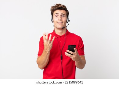 Young Handsome Man Looking Desperate, Frustrated And Stressed With A Smartphone And Headset