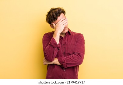 Young Handsome Man Looking Stressed, Ashamed Or Upset, With A Headache, Covering Face With Hand