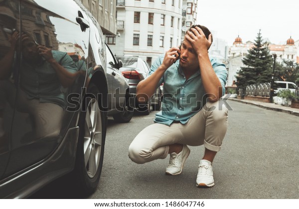 young handsome man looks\
nervous car broke in the middle of the road calling to service\
station