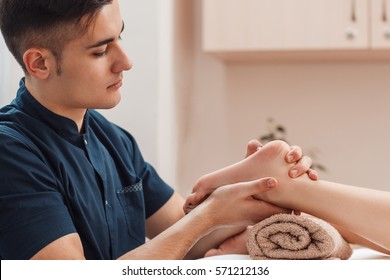 Young Handsome Man Massaging Bare Female Foot Free Space. Male Masseur Relaxing Beautiful Woman Leg. Foot Fetish, Beauty, Body Care, Desire, Rest, Stress Relief Concept