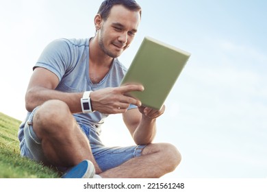 young and handsome man with mobile tablet sitting in the park 