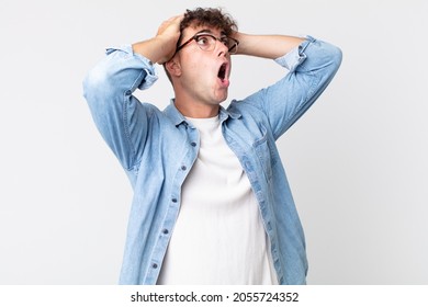 young handsome man with open mouth, looking horrified and shocked because of a terrible mistake, raising hands to head - Shutterstock ID 2055724352