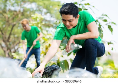 Young handsome man picking up litter in the forest - Powered by Shutterstock