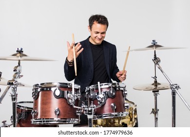 Young handsome man play with drumsticks sitting at drums isolated on white background - Powered by Shutterstock