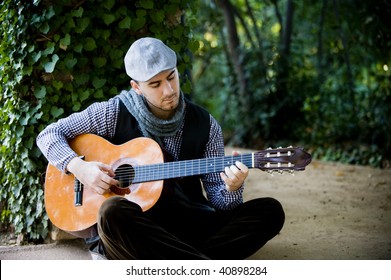 Young Handsome Man Playing Spanish Guitar In Green Garden