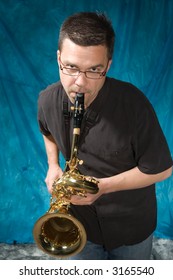 Young Handsome Man Posing In Front Of Portrait Backdrop With Saxaphone