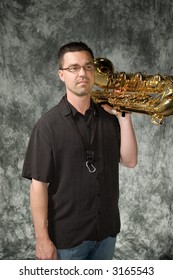 Young Handsome Man Posing In Front Of Portrait Backdrop With Saxaphone