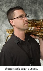 Young Handsome Man Posing In Front Of Portrait Backdrop With Saxaphone