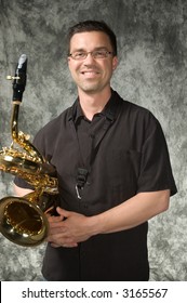 Young Handsome Man Posing In Front Of Portrait Backdrop With Saxaphone