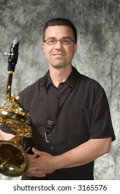 Young Handsome Man Posing In Front Of Portrait Backdrop With Saxaphone