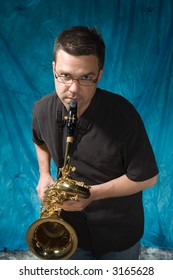 Young Handsome Man Posing In Front Of Portrait Backdrop With Saxaphone