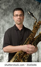 Young Handsome Man Posing In Front Of Portrait Backdrop With Saxaphone