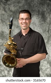 Young Handsome Man Posing In Front Of Portrait Backdrop With Saxaphone