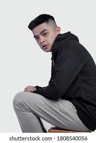 Young Handsome Man Posing And Sit In A Chair Wearing Black Zip Hoodie