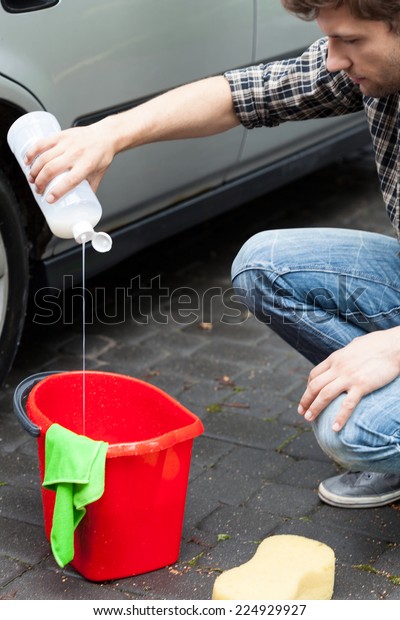 Young\
handsome man preparing cleaner to wash his\
car