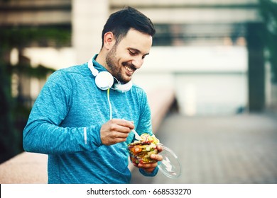 Young Handsome Man Is Relaxing And Eating Fruit Salad.