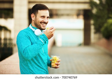 Young Handsome Man Is Relaxing And Eating Fruit Salad.