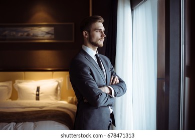 Young Handsome Man Relaxing At His Apartment In A Hotel After Business Meeting. Business Trip. Booking Hotel During Your Vacation. Businessman In Luxury Room  Of The Expensive Beautiful Hotel. 