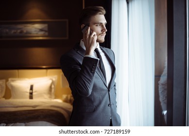 Young Handsome Man Relaxing At His Apartment In A Hotel After Business Meeting. Business Trip. Booking Hotel During Your Vacation. Businessman In Luxury Room  Of The Expensive Beautiful Hotel. 