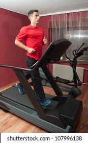 Young Handsome Man Running On Treadmill In Home Made Gym.