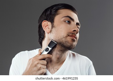 Young handsome man shaving over grey background. - Shutterstock ID 461991235