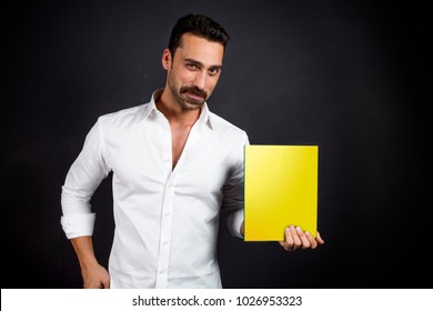 Young Handsome Man Showing A Magazine Or Book, Studio Portrait, Magazine Cover Isolated With Clipping Paths