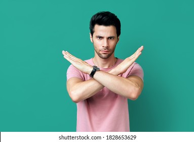 Young handsome man showing stop sign on blue background. Prohibition symbol