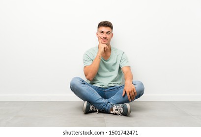 Young handsome man sitting on the floor thinking an idea