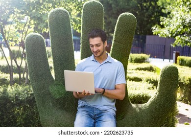 Young Handsome Man Sitting In The Park And Working On Laptop