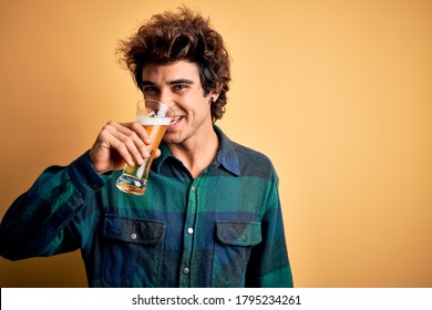Young handsome man smiling happy. Standing with smile on face drinking glass of beer over isolated yellow background - Powered by Shutterstock