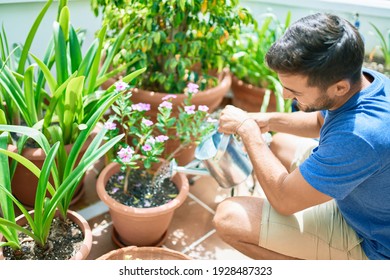 Young handsome man smiling happy caring plants using watering can at terrace - Powered by Shutterstock