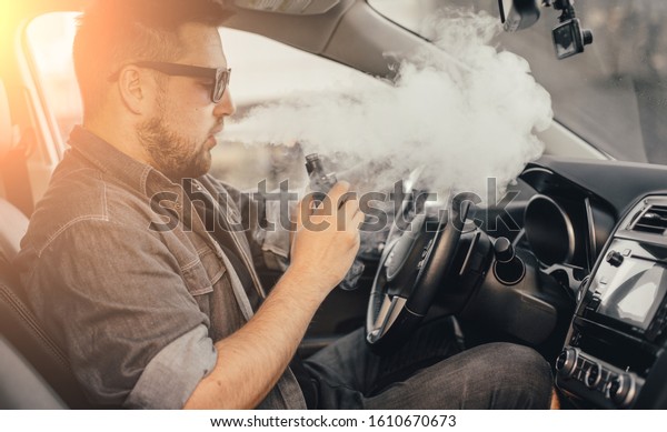 Young handsome\
man smoke with vape in\
vehicle