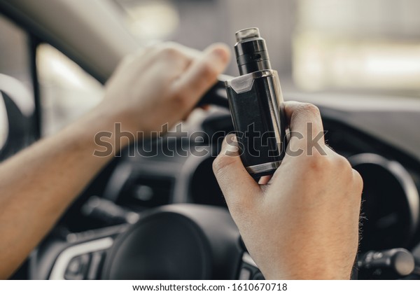 Young handsome\
man smoke with vape in\
vehicle